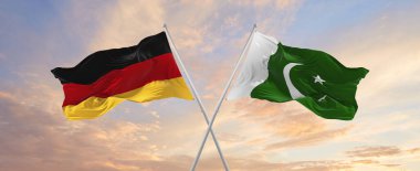 Almanya ve Pakistan 'ın bayrak direkleri rüzgarda dalgalanırken güneşli bir günde gökyüzüne karşı bulutlar. İki ülke arasındaki ilişkiyi, diyaloğu sembolize ediyor. 3d illüstrasyon,
