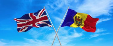 Büyük Britanya ve Moldova 'nın bayrakları rüzgarda dalgalanırken bayrak direkleri gökyüzüne karşı güneşli bir günde bulutlarla. İki ülke arasındaki ilişkiyi, diyaloğu sembolize ediyor. 3d illüstrasyon,