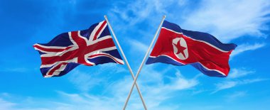 Büyük Britanya ve Kuzey Kore 'nin bayrakları rüzgarda dalgalanır bayrak direkleri gökyüzüne karşı güneşli bir günde bulutlarla. İki ülke arasındaki ilişkiyi, diyaloğu sembolize ediyor. 3d illüstrasyon,