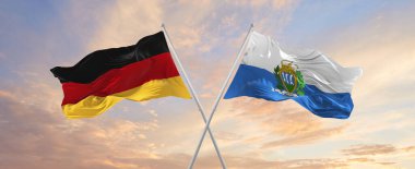 Almanya ve San Marino 'nun bayrakları rüzgarda dalgalanırken bayrak direkleri gökyüzüne karşı güneşli bir günde. İki ülke arasındaki ilişkiyi, diyaloğu sembolize ediyor. 3d illüstrasyon,