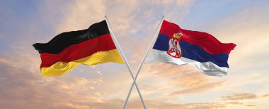 Almanya ve Sırbistan 'ın bayrakları, güneşli bir günde gökyüzüne doğru bayrak direkleri sallıyor. İki ülke arasındaki ilişkiyi, diyaloğu sembolize ediyor. 3d illüstrasyon,
