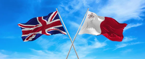 在阳光明媚的日子 大不列颠和马耳他的国旗在风中飘扬 旗杆迎着天空飘扬 象征两国关系 两国间的对话 3D说明 — 图库照片