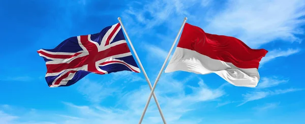 晴れた日には雲と空に向かって旗竿で風になびくイギリスとモナコの国旗 関係を象徴し 両国間の対話 3Dイラスト — ストック写真