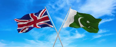 Büyük Britanya ve Pakistan 'ın bayrakları güneşli bir günde gökyüzünde bayrak direkleri sallıyor. İki ülke arasındaki ilişkiyi, diyaloğu sembolize ediyor. 3d illüstrasyon,