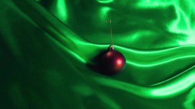 Yeşil İpek 'te Noel Bauble - Kırmızı bir Noel mücevheri yeşil ipek üzerinde yavaşça ilerliyor. Noel videoları, TV reklamları, vloglar, sosyal paylaşımlar, yaratıcı gönderiler, hareket grafikleri ve daha fazlası için harika.