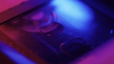 Video Teybi Odaklanma Çekimi - Bir video kasetin içindeki manyetik şerit bu güzel neon ışıklı makro çekimde odaklanıyor. Retro atari tarzı filmler, sinematik yayınlar, müzik videoları ve daha fazlası için harika bir video..