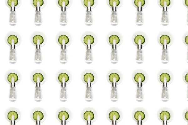 Pattern from cosmetic drop bottle and sliced cucumber isolated on the white background. Natural cosmetics.