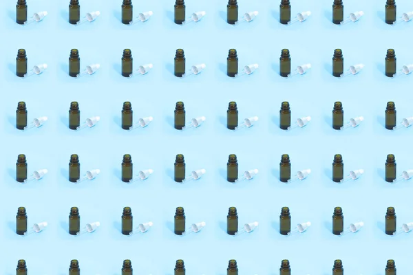 Pattern from cosmetic jar of glass dropper with white rubber tip on the blue background. Nature Skin concept.