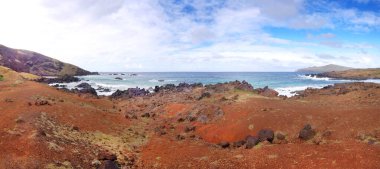 Paskalya Adası 'ndaki sahilin panoramik manzarası, beyaz bulutlarla kaplı mavi gökyüzüne karşı..