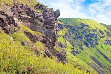 Paskalya Adası 'ndaki Rano Kau yanardağının yamaçlarının manzarası, açık mavi gökyüzüne karşı yeşil bitki örtüsüyle kaplı..