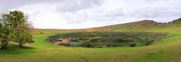 Vue panoramique à l'intérieur du cratère du volcan Rano Raraku sur l'île de Pâques, contre un ciel bleu, couvert de nuages blancs. — Photo