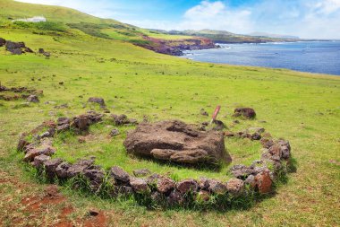 Moai kafası, Vinapu 'nun merasim merkezinde okyanusa karşı Rapa Nui adında bir taş yapı ve beyaz bulutlarla kaplı mavi bir gökyüzü ile çevrilidir..