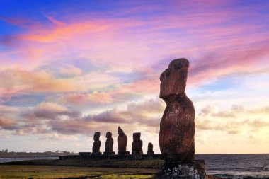 Paskalya Adası 'ndaki Ahu Tahai törensel kompleksindeki Moai heykelleri renkli bir günbatımı gökyüzüne karşı..