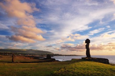 Paskalya Adası 'ndaki Ahu Tahai törensel kompleksindeki Moai heykelleri renkli bir günbatımı gökyüzüne karşı..