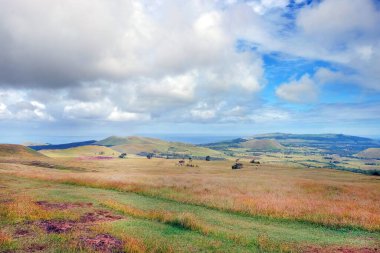 Paskalya Adası 'ndaki Terevaka Volkanı' nın yamaçlarından panoramik manzara yeşil bitki örtüsünü ve okyanusu mavi gökyüzüne karşı gösteriyor..