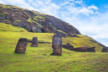 Rano Raraku Volkanı 'nın yamaçlarında, Easer Adası' nda, beyaz bulutlarla kaplı mavi gökyüzüne karşı..