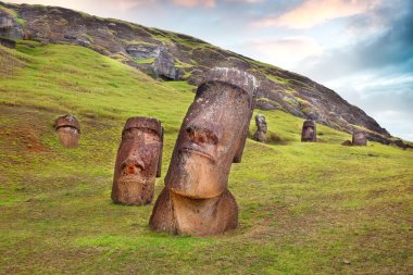 Rano Raraku Volkanı 'nın yamaçlarında Moai, Easer Adası' nda, yeşil bitkilerle çevrili, renkli bir gökyüzüne karşı..