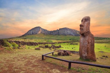 Paskalya Adası 'ndaki Ahu Tongariki merasim merkezinin girişindeki taş çit ve Moai heykelleri Rano Raraku volkanı kraterine karşı renkli bir günbatımı gökyüzü ile kaplıydı..