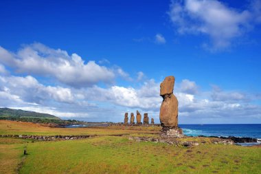 Paskalya Adası 'ndaki Ahu Tahai törensel kompleksindeki Moai heykelleri beyaz bulutlarla kaplı mavi gökyüzüne karşı..