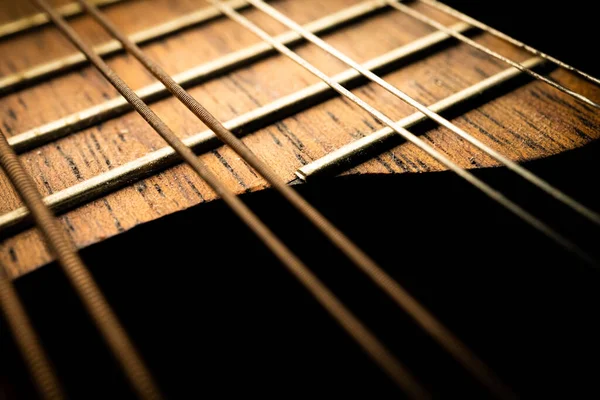Karanlıkta mandolin fretboard 'un kıvrımlı sonunun makro fotoğrafı ve görülebilir bir vücudu yok.
