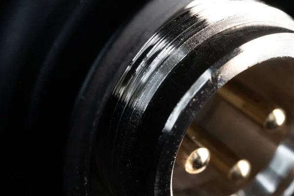 Closeup of worn out threads on bottom of condenser microphone with XLR pins out of focus