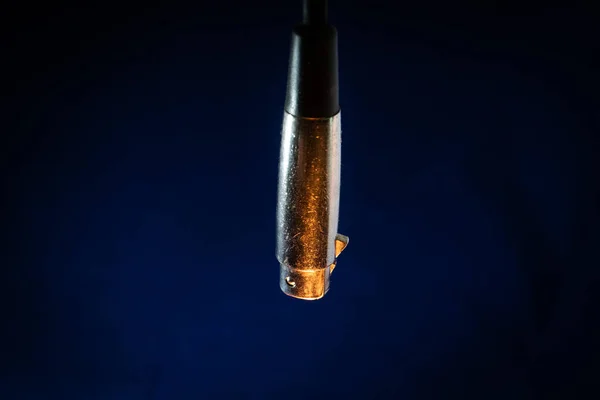Dangling 'in Kapanışı Eskimiş ve Çizilmiş Erkek XLR Bağlantısı Orange Lighting ile Mavi Arkaplanda izole edildi