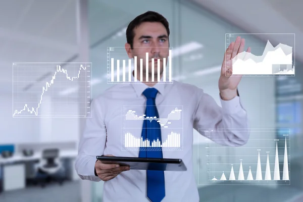 Man working in his office,holding his tablet and looking at charts — Stockfoto