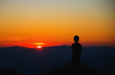 Gün batımı ve düşünmek bakarak yalnız bir çocuk....