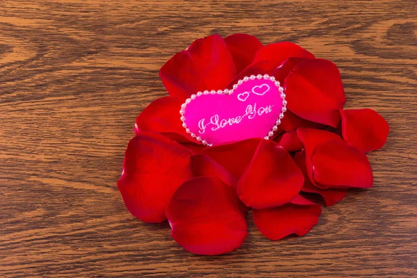 Płatki róż i różowego serca na tle drewniane — Zdjęcie stockowe