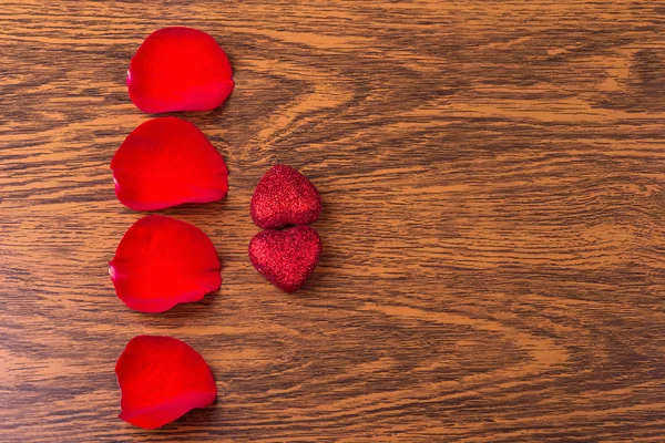 Pojęcie romans: płatki czerwonych róż i dwa serca — Zdjęcie stockowe