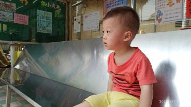 Asyalı Tayvanlı çocuk otobüs durağında oturmuş otobüs bekliyor.