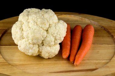 Karnabahar ve siyah arka plan ile ahşap tabakta havuç