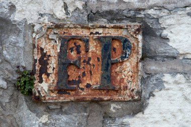 Eski bir yangın musluğu işaret levhası antik bir taş duvarda