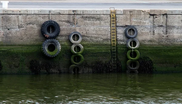 Giriş merdiveni ve eski lastikleri olan eski liman duvarı.