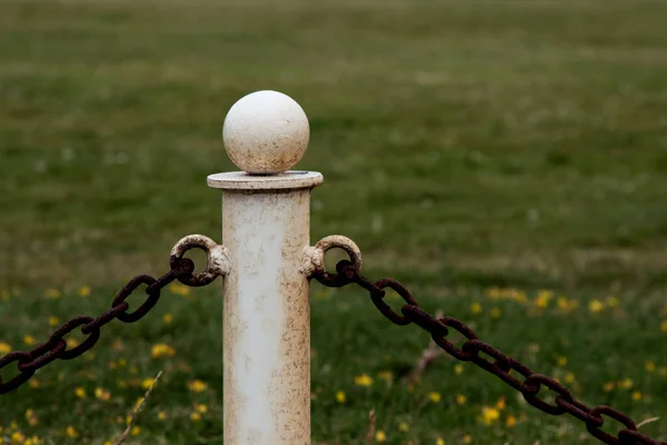 Old metal chain fence stanchion with chain fence in a country park