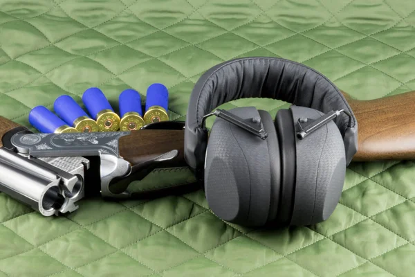 Shotgun with ear protection and cartridges on an outdoor coat