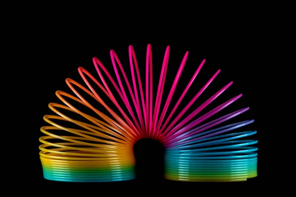 Colorido Juguete Resorte Slinky Aislado Sobre Fondo Negro Fotos de stock