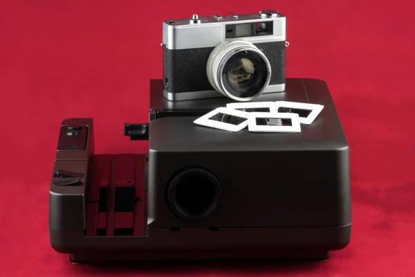 Old film camera with slide projector and slides on a red background