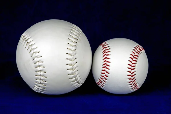 Small and large softballs isolated against a blue background