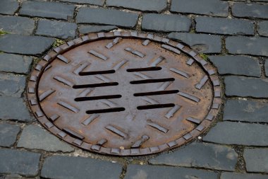 Köyün kaldırımlı eski bir sokağında metal rögar kapağı.