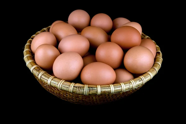 Ein Whicker Korb mit frischen Hühner Eier vor einem schwarzen Hintergrund isoliert