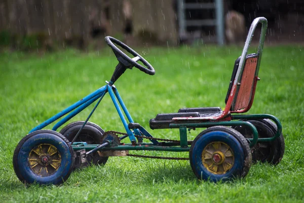 Old children's car, standing on green grass in the rain. — Stock Photo, Image