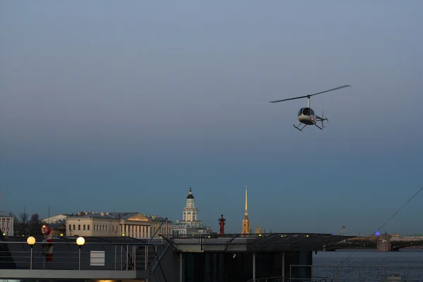 Kentsel peyzaj arka plan üzerinde helikopter iniyor.