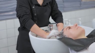 Profesyonel bir güzellik salonu çalışanı saçını yıkıyor. Şampuanla temizle ve saçına saç kremiyle masaj yap. Güzellik salonu, saç bakımı ve insanların konsepti.