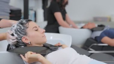 Profesyonel bir güzellik salonu çalışanı saçını yıkıyor. Şampuanla temizle ve saçına saç kremiyle masaj yap. Güzellik salonu, saç bakımı ve insan konsepti