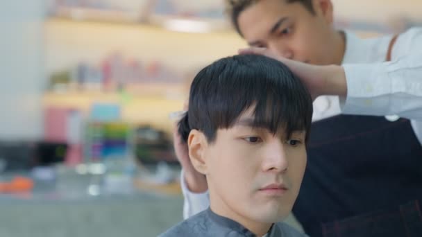 プロの理容師アジア人男性は 彼の理容師の店で顧客のための髪をトリミングするためにはさみや櫛を使用します 美容室 理容室事業コンセプト — ストック動画