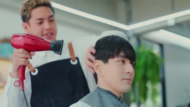 スローモーション アジアのプロの美容師男性スタイリストは 顧客の体と頭からカット髪の男性の顧客を追跡するためにヘアドライヤーを使用しています 美容室理容室理容室ショップ ヘアカットコンセプト — ストック動画