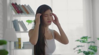 Beyaz pijamalı güzel bir kadın yatak odasında yatağında oturuyor. Ateşi ve iş yerindeki stresten kaynaklanan kronik migren krizleri yüzünden şiddetli baş ağrıları var..