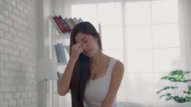 Asyalı bir kadın yatakta tekrar eden alerjisi yüzünden burnunu bastırıyor. Burnu akacak, başı ağrıyacak ve bazen ateşi çıkacak..