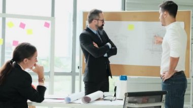 Mühendis ve mimarlardan oluşan bir ekip, proje planlarını modern bir ofiste tartışmak için Beyin Fırtınası 'nda toplanıyor. Ağır çekim. Bir plandan bahset..